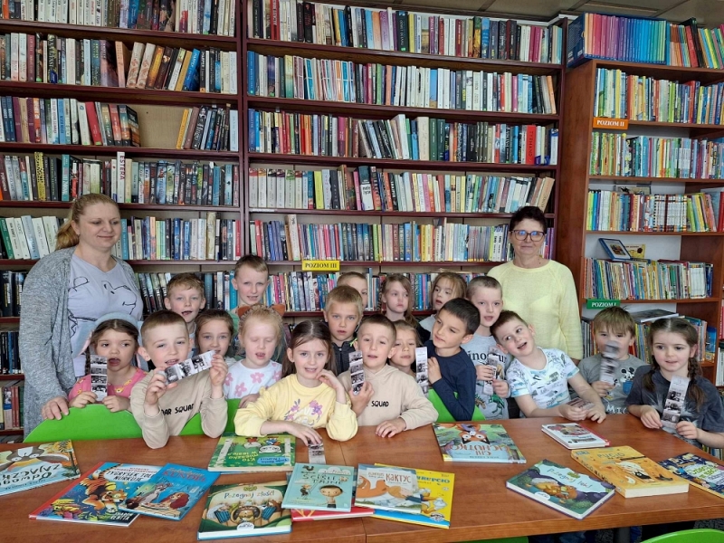 Dzieci w bibliotece, zdjęcie grupowe na tle regału z książkami