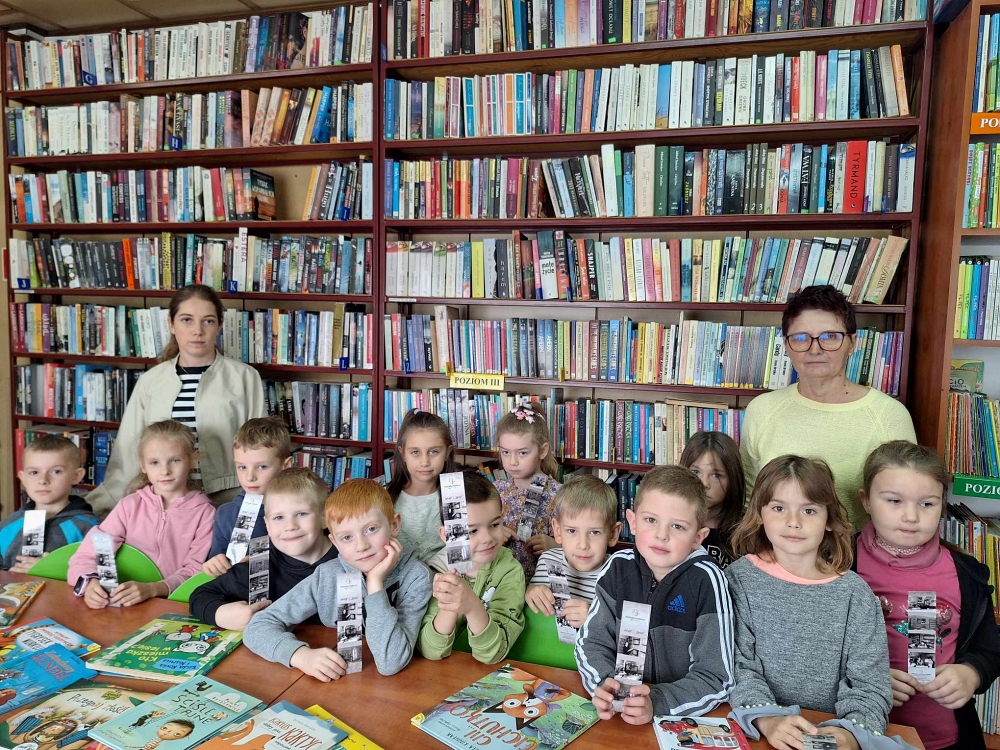 Dzieci w bibliotece na tle księgozbioru  na regale