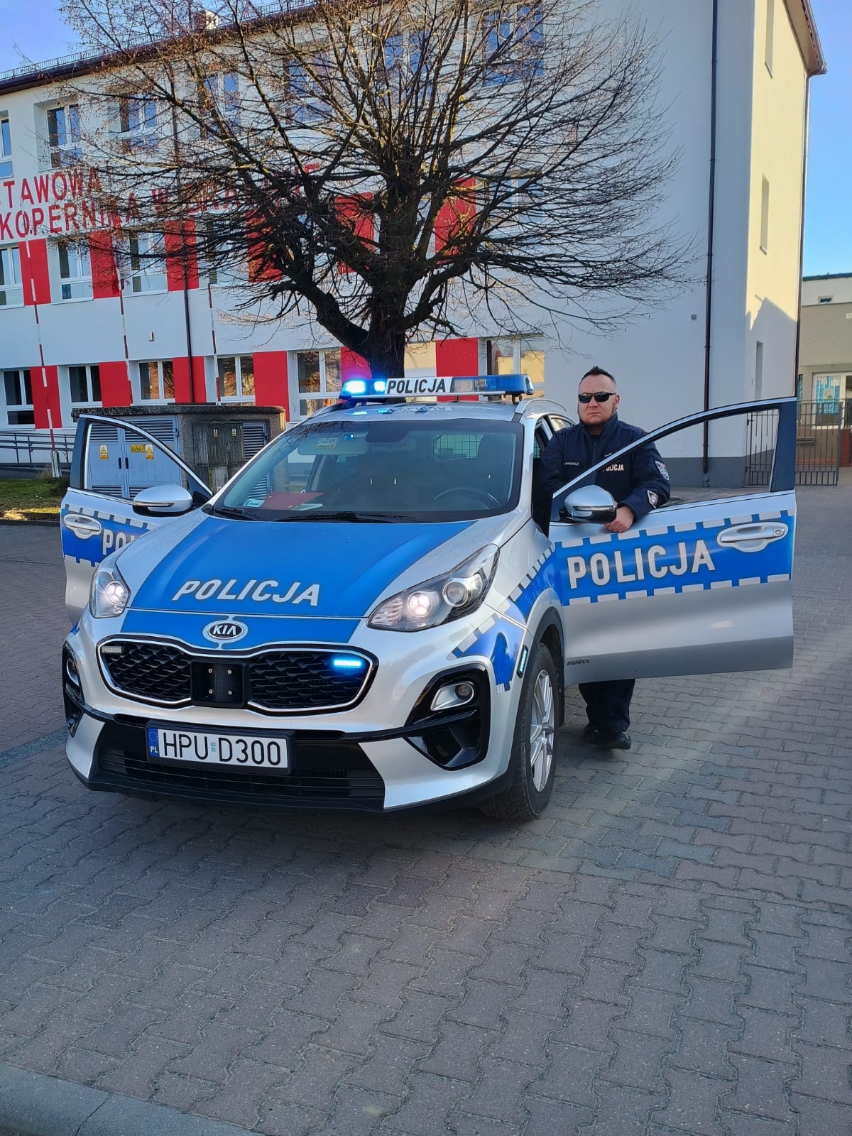 Policjant w mundurze przy samochodzie policyjnym