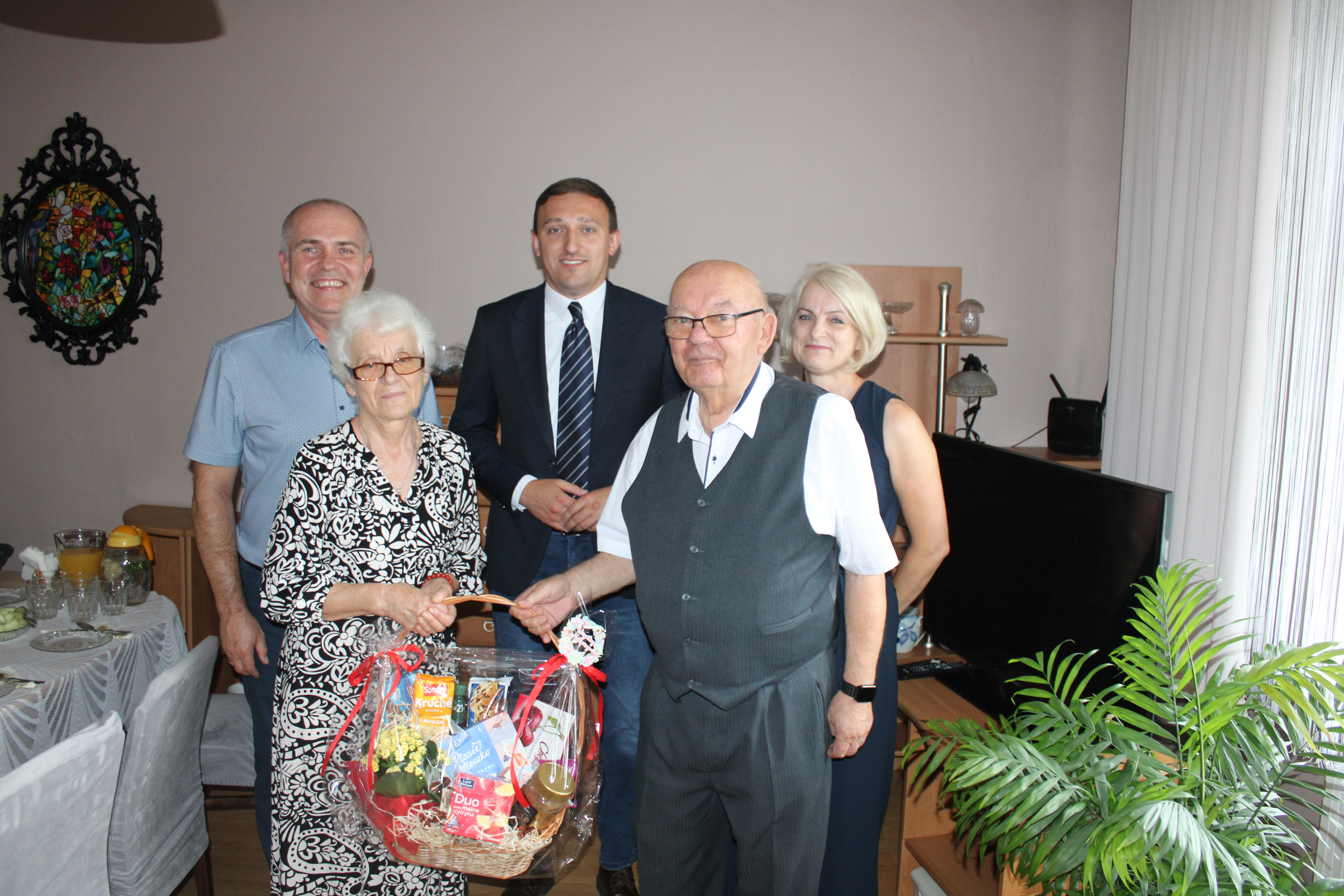 Na zdjęciu trzech mężczyzn i&nbsp;dwie kobiety, z&nbsp;przodu para trzyma kosz prezentowy