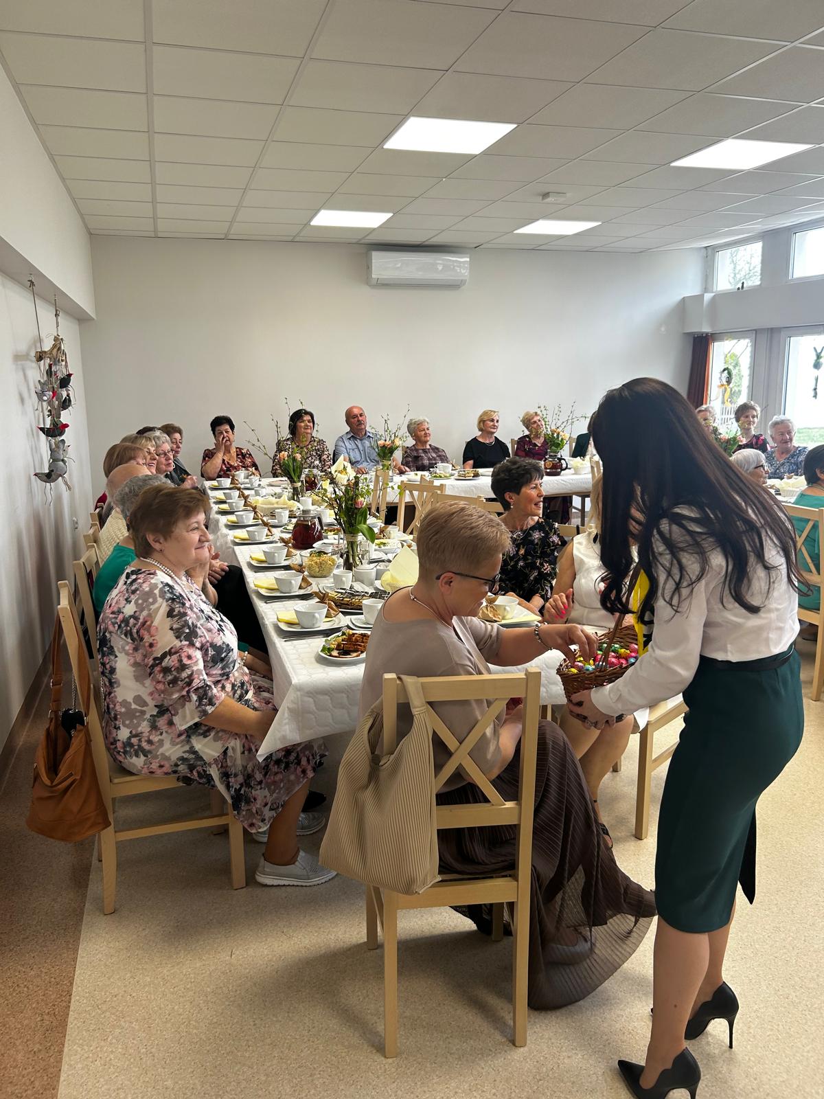 Pani w białej koszuli częstuje jajeczkami w koszu