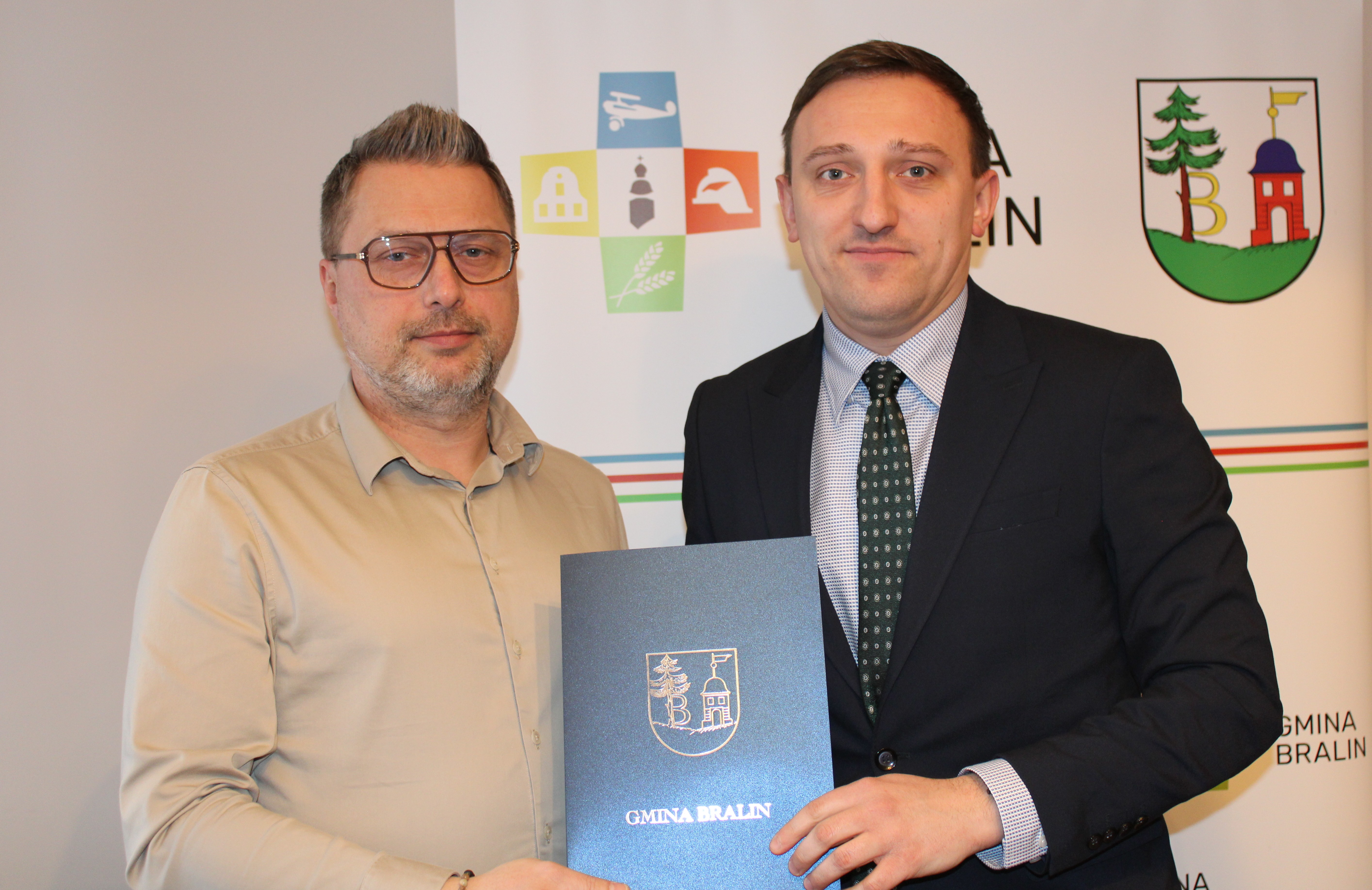 Podpisanie umowy z&nbsp;UKS Sport, dw&oacute;ch mężczyzn trzyma teczkę gminy