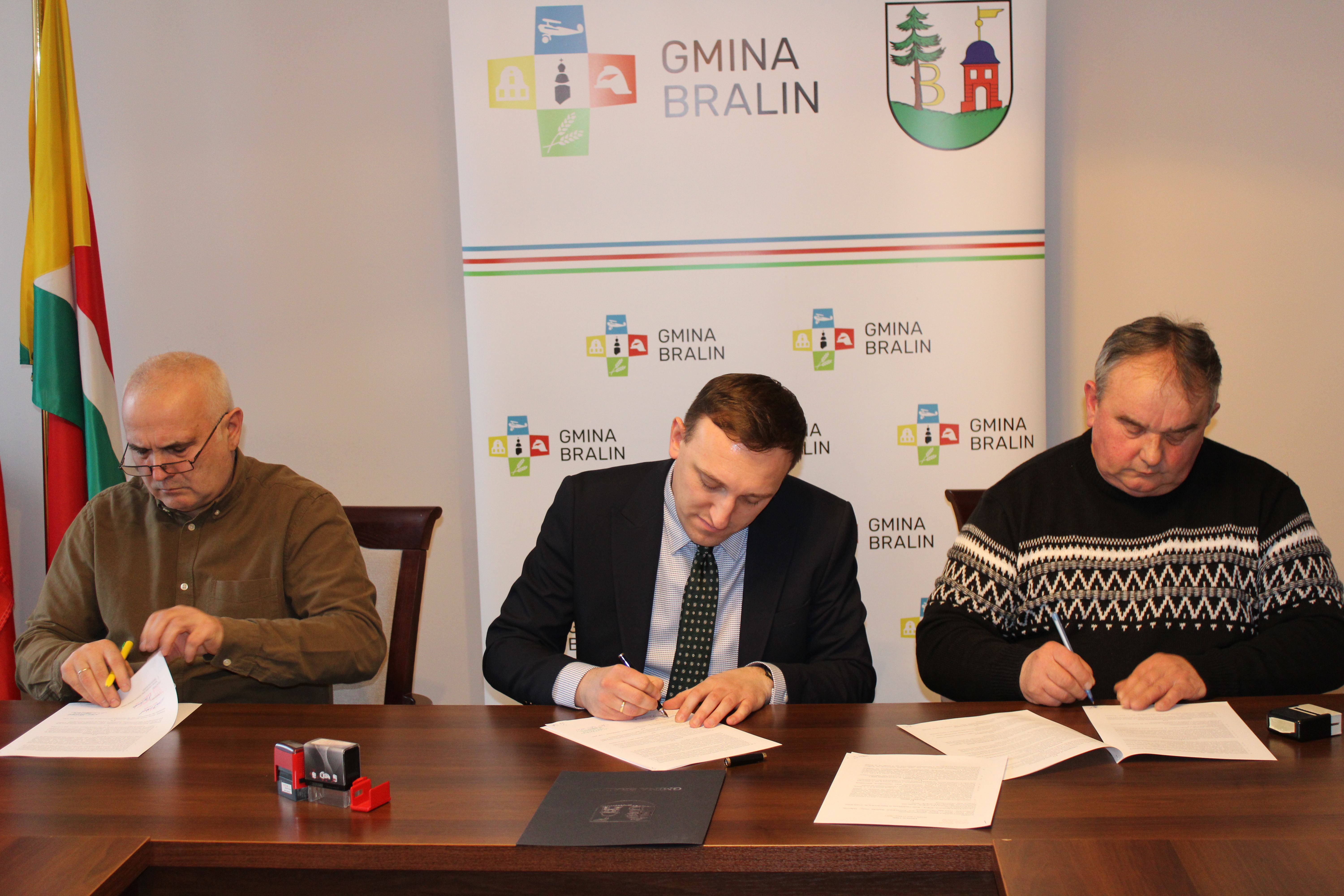 Podpisanie umowy, trzech mężczyzn podpisuje umowę