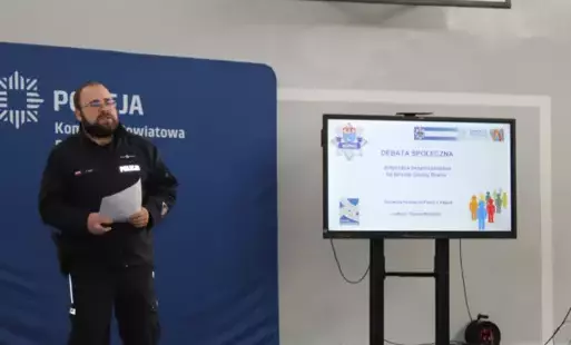 Policjant w mundurze na tle baneru policyjnego